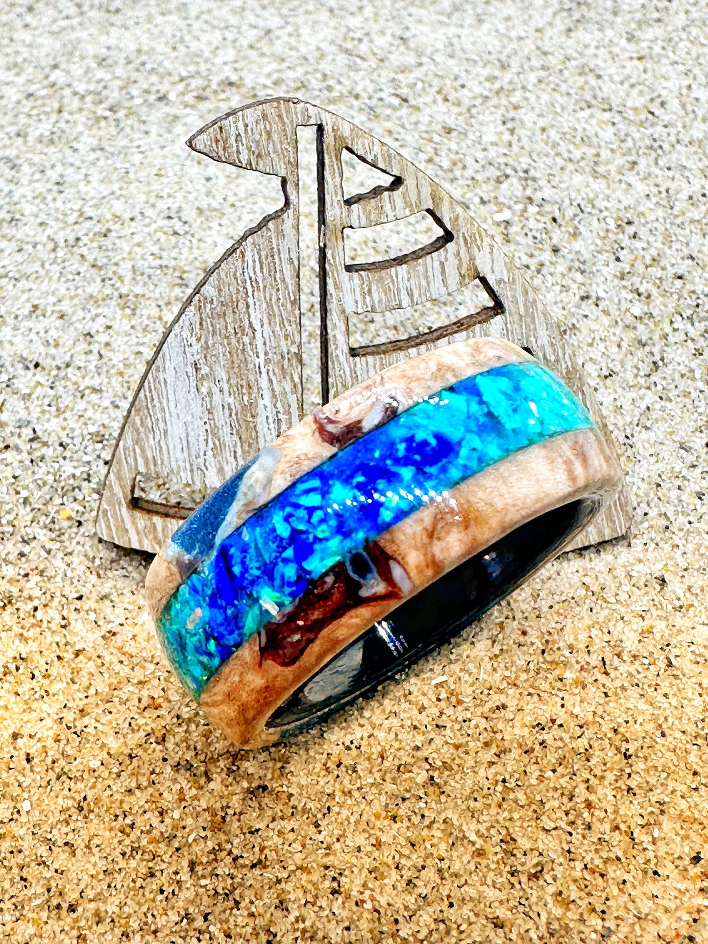 Handgefertigter Ring, gefüllt mit Sand und kleinen Elementen vom Strand. Transparente Harzschicht bewahrt die Struktur des Strandes und macht ihn als tragbare Erinnerung erlebbar.
Handmade ring filled with sand and small elements from the beach. A transparent resin layer preserves the texture of the shore, turning it into a wearable memory.