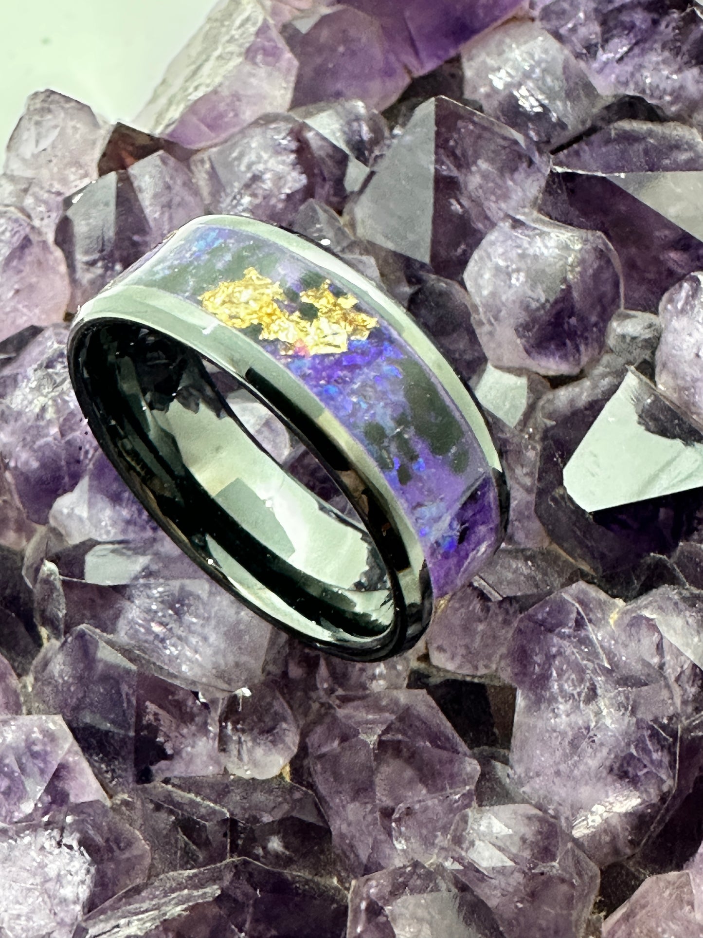 Handgefertigter Ring New Orleans, mit goldfarbenen Elementen, inszeniert auf einer Amethystdruse. Der Kontrast zwischen schimmerndem Gold und den violetten Kristallen des Amethysts verstärkt die mystische Ausstrahlung des Schmuckstücks.
Handmade New Orleans ring with golden elements, displayed on an amethyst druse. The contrast between the shimmering gold and the violet crystals of the amethyst enhances the mystical aura of the jewel.