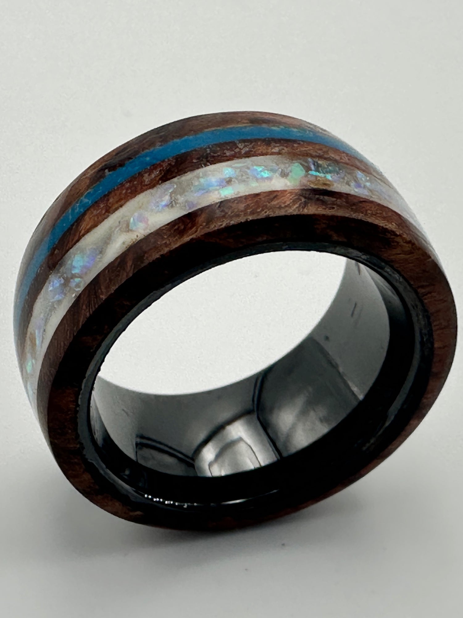Makroaufnahme
🇩🇪 „Ring Winter – Makroaufnahme, Opalstreifen in Blau und Weiß leuchten im dunklen Ebenholz“
🇫🇷 « Bague Winter – gros plan, bandes d’opale bleue et blanche scintillant dans l’ébène sombre »
🇬🇧 “Ring Winter – macro view, blue and white opal stripes glowing within dark ebony”