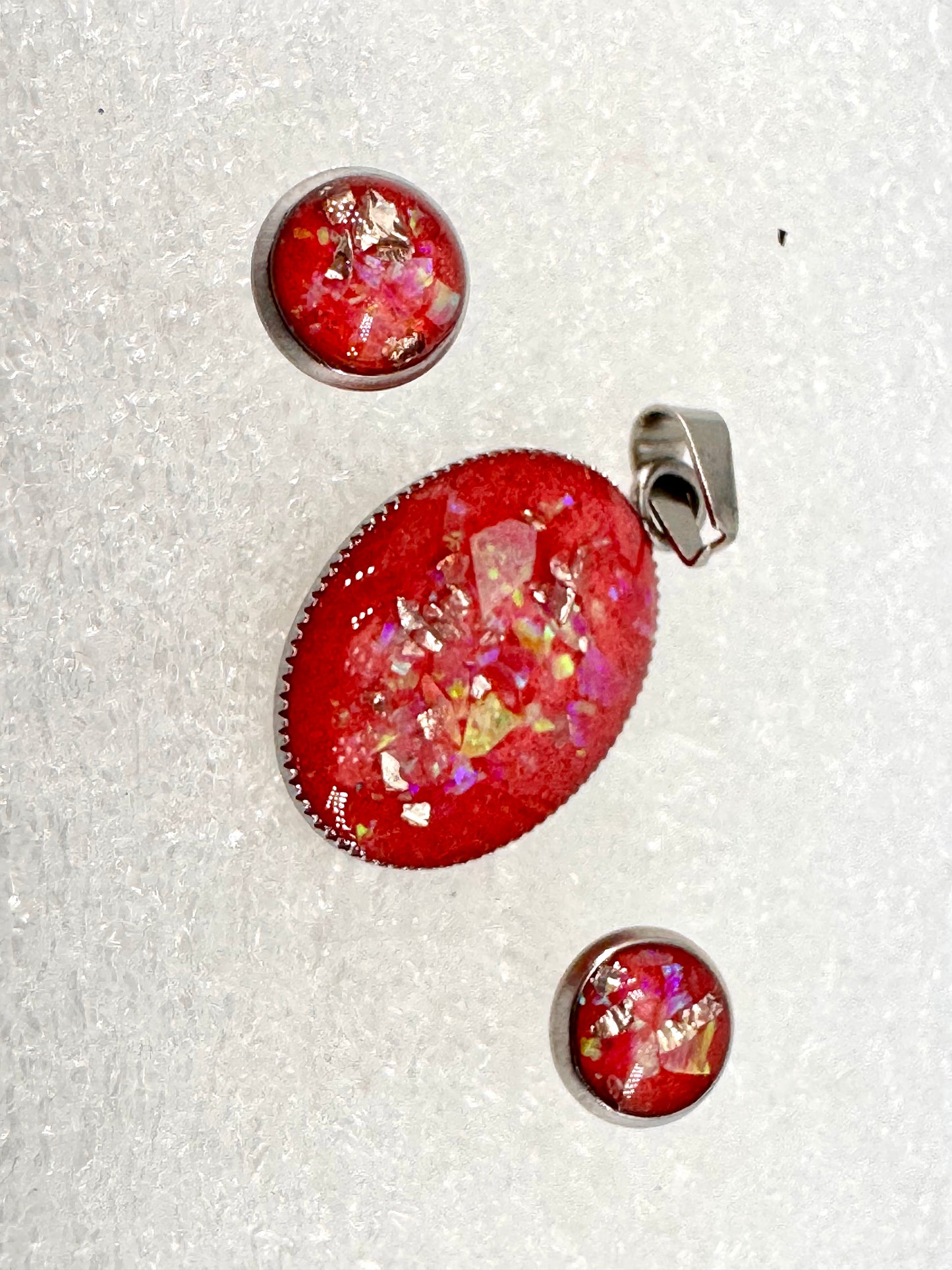 Schmuckset aus Edelstahl mit ovalem Amulett und Ohrsteckern – rotes Kunstharz mit schillernden Opalfragmenten, handgefertigt in Nathalies Atelier. Ein Unikat, das Feuer, Licht und Lebenskraft vereint
