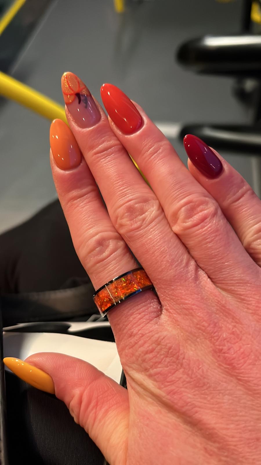 Schwarzer Keramikring mit orangefarbenen Opalen, getragen an einer Hand mit Halloween-Nägeln. Der Ring funkelt in Kürbisfarben und wirkt wie ein echter Halloween-Ring. Black ceramic ring with orange opals, worn on a hand with Halloween-themed nails. The ring sparkles in pumpkin tones, capturing the spirit of Halloween.