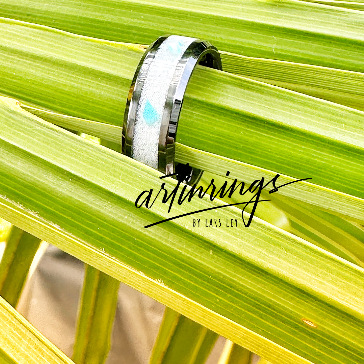 Schwarzer Keramikring, gefüllt mit weißem Brautkleidstoff und blauen Opalen. Der helle Stoff im Kontrast zum tiefen Schwarz der Keramik wird von den schimmernden Blautönen der Opale akzentuiert – ein Ring voller Symbolik von Liebe und Ewigkeit.

Black ceramic ring filled with white bridal dress fabric and blue opals. The light fabric contrasts with the deep black ceramic, highlighted by the shimmering blue tones of the opals – a ring full of symbolism of love and eternity.