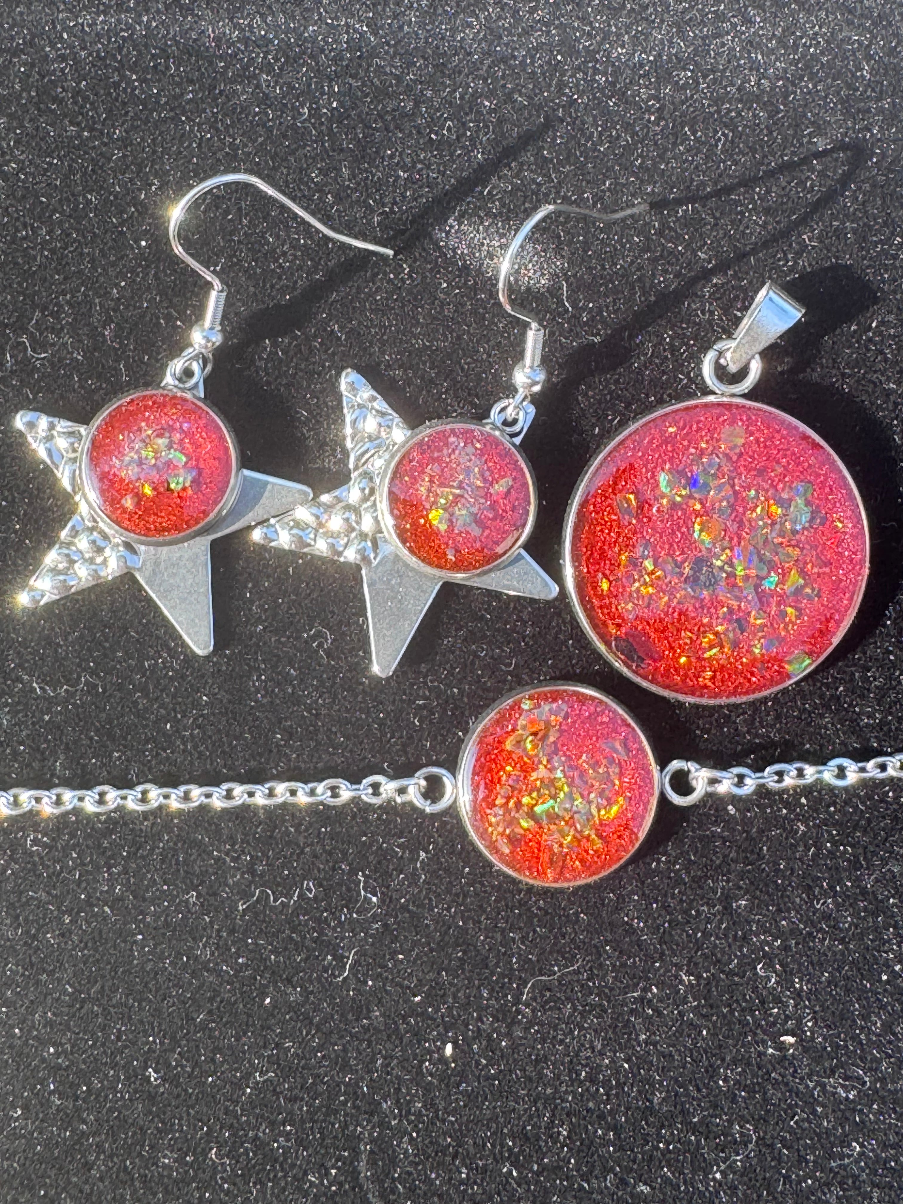 Ein Schmuckset aus Edelstahl, durchzogen von glühend roten Pigmenten, in denen farbig schillernde Opale wie kleine Flammen aufleuchten – ein Ausdruck von Kraft und lebendiger Eleganz