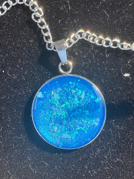 Handgefertigtes Amulett, 4 cm groß, mit dunkelblauen Opalen. Die schimmernden Opale in tiefem Blau entfalten auf der größeren Fläche eine intensive, geheimnisvolle Ausstrahlung.

Handmade amulet, 4 cm in size, with dark blue opals. The shimmering deep-blue opals unfold a strong, mysterious radiance on the larger surface.