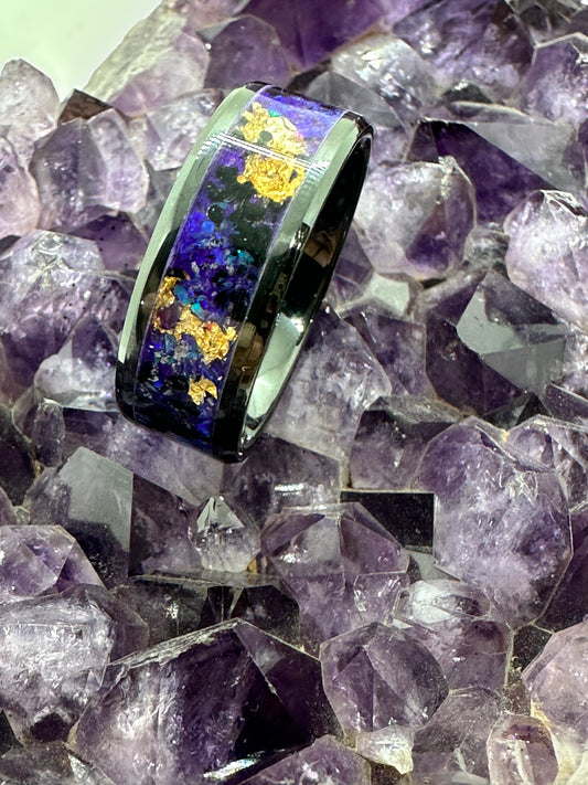 Handgefertigter Ring New Orleans, mit goldfarbenen Elementen, inszeniert auf einer Amethystdruse. Der Kontrast zwischen schimmerndem Gold und den violetten Kristallen des Amethysts verstärkt die mystische Ausstrahlung des Schmuckstücks.

Handmade New Orleans ring with golden elements, displayed on an amethyst druse. The contrast between the shimmering gold and the violet crystals of the amethyst enhances the mystical aura of the jewel.