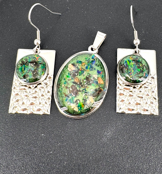 Schmuckset aus Edelstahl mit Kunstharz, Farbpigmenten und schimmernden Opalen – bestehend aus einem ovalen Amulett und passenden Ohrringen. Grüntöne, Kupferreflexe und Lichtspiele verschmelzen zu einem modernen Relikt der Erde