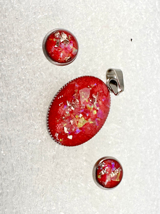 Schmuckset aus Edelstahl mit ovalem Amulett und Ohrsteckern – rotes Kunstharz mit schillernden Opalfragmenten, handgefertigt in Nathalies Atelier. Ein Unikat, das Feuer, Licht und Lebenskraft vereint