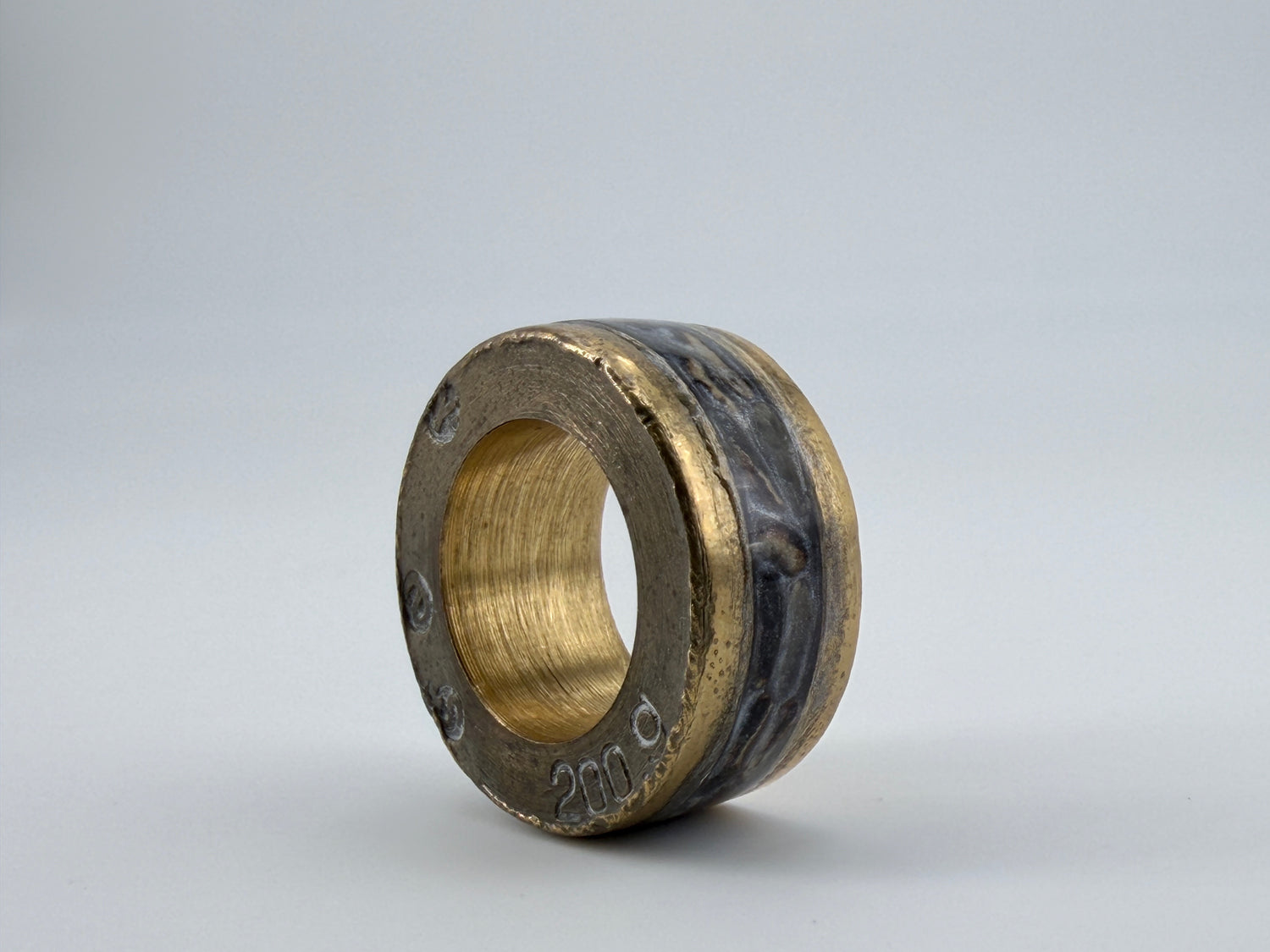Handcrafted ring sculpture symbolizing Hunger, featuring layered organic materials and a warm gold-toned interior core.