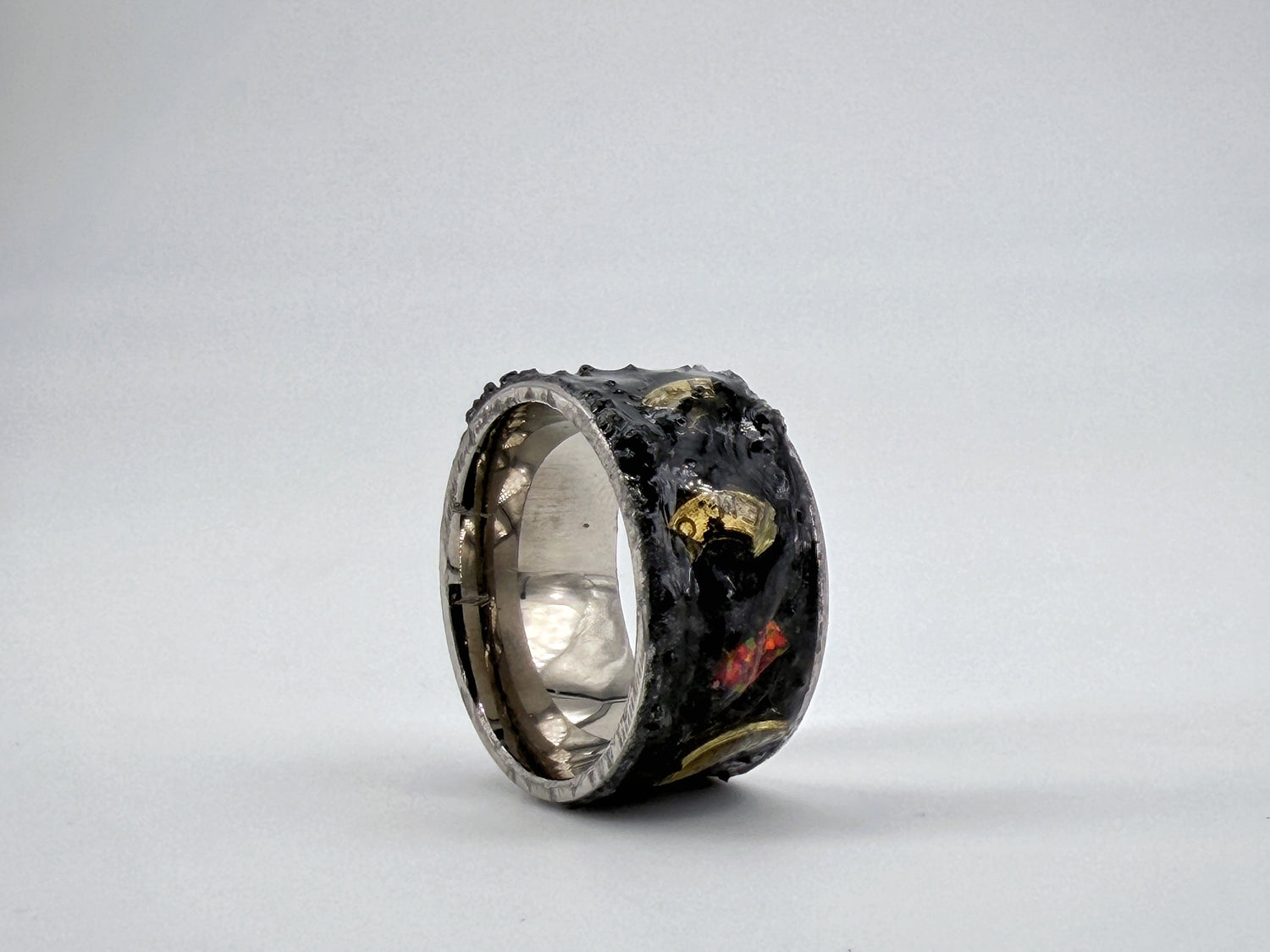 Dark mixed-media ring sculpture symbolizing War, incorporating textured black materials and red accents within a steel structure.