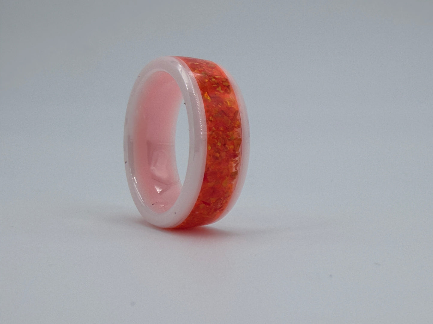 Ring aus weisser Keramik, gefüllt mit orangen Opalen, handgefertigt im Atelier Artinrings.