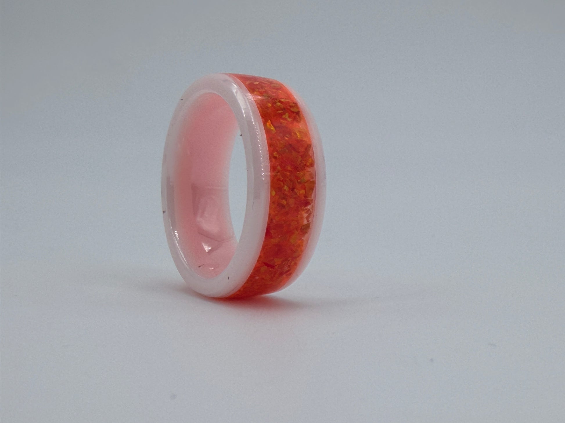Ring aus weisser Keramik, gefüllt mit orangen Opalen, handgefertigt im Atelier Artinrings.