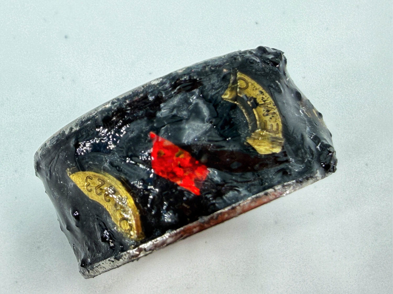 Dunkle Mixed-Media-Ring­skulptur „War“ aus der Serie Apokalyptische Reiter – strukturierte schwarze Materialien mit roten Akzenten in einer Stahlfassung.
